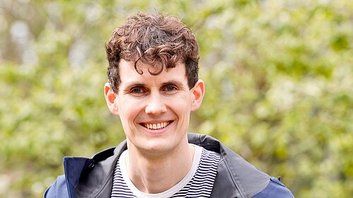 Josh Matthews in front of a green background