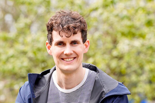 Josh Matthews smiling in front of a green background